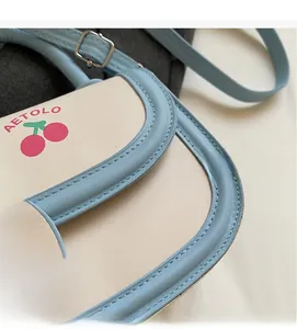 Close-up of sky blue saddle bag with cherry prints and textured PU leather stitching