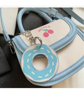 Detail view of light blue and white crossbody bag with cherry print and donut charm
