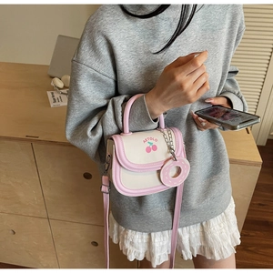 Details einer cremefarbenen Satteltasche mit Kirschprint und rosa Donut-Anhänger