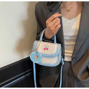 Detail der süßen blauen Satteltasche mit Kirschmuster und Donut-Anhänger am Model