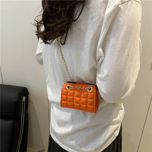 Orange quilted leather mini crossbody bag with gold chain strap worn by a model