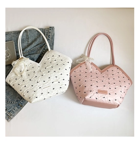 Detail of cream and pink tote bags featuring bow embroidery, lace trim, and pearl charms