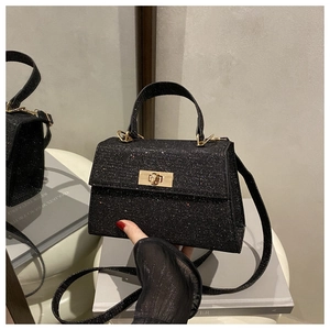 Close-up of elegant black sequin handbag with gold metal lock on a white chair