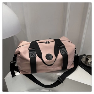 Detail of pink waterproof travel bag with logo, nylon texture, and detachable shoulder strap