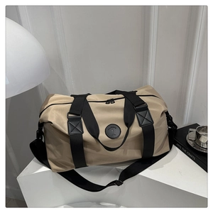 Detail of khaki oxford travel bag featuring durable handles and numerical logo on a pedestal