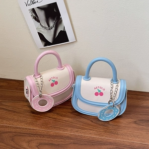 Schicke cremeweiße Satteltaschen mit Kirschprint und Donut-Anhänger auf Holztreppe