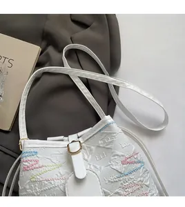 Close-up of white canvas bucket bag featuring colorful wave stitching and gold hardware