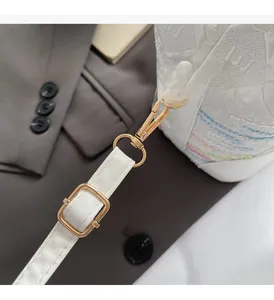 Detail of white textured bucket bag featuring elegant gold hardware and leather strap