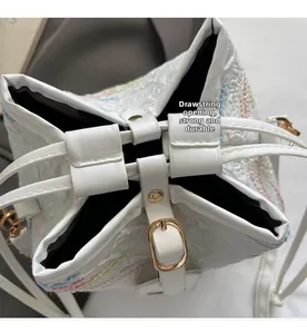 Detail of white bucket bag with drawstring closure and golden metal buckle hardware