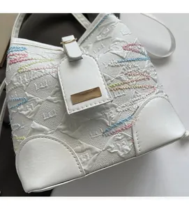 Detail of white bucket bag with colorful embroidery and gold metal hardware accents