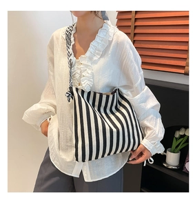 Detail of canvas tote bag featuring black and white vertical stripes and geometric strap