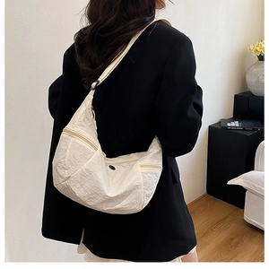 Borsa a tracolla beige a mezzaluna mostrata su modella per un look urbano chic