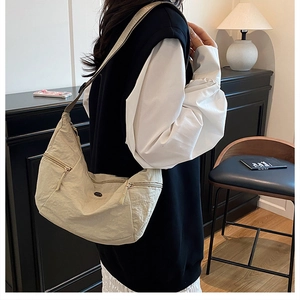 Dettaglio della borsa hobo beige in nylon stropicciato con tasche laterali con zip