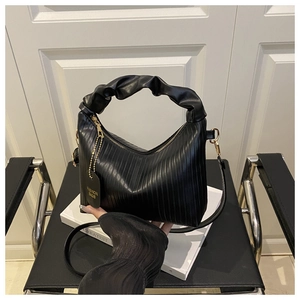 Detail view of black pleated crescent handbag with gold zipper and ruffles
