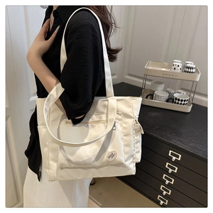 Detail of cream canvas tote bag showing 'good luck!' embroidery and side pocket storage