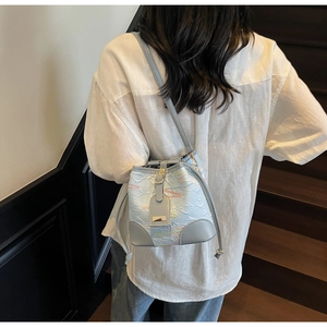 Detail view of light blue bucket bag showing textured fabric and grey leather accents