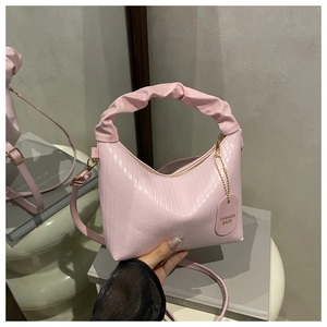 Détail d'un sac à main plissé rose avec textures verticales et poignée en nuage