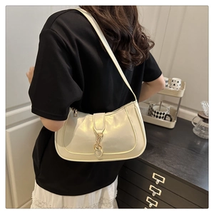 Detail of a cream faux leather crescent hobo bag with a gold piston closure and stitching