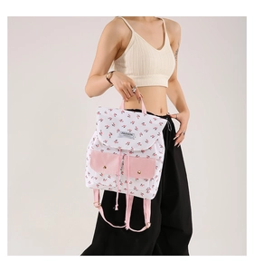 Floral canvas backpack detail with pink front pockets and decorative letter patch
