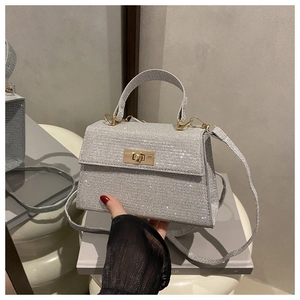 Detailed view of silver rhinestone handbag with gold-tone lock and sparkly texture