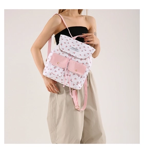 Detailed close-up of a floral canvas backpack featuring a pink flap and fashion label
