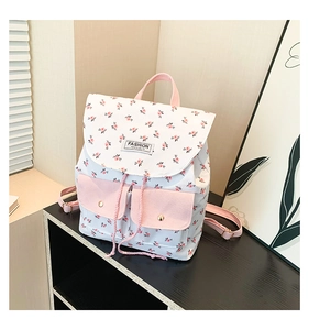 Close-up of floral backpack showing front pockets with gold snaps and FASHION INSTINCT label