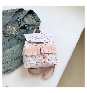 Detail of floral canvas backpack with pink pockets and drawstring closure on denim jacket