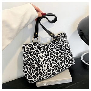 Detail of leopard print tote bag with black leather straps and gold metal rings