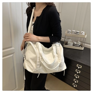 Detailed view of a white large capacity tote bag with soft leather texture and side drawstrings