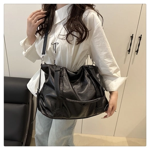 Detail of black lychee grain PU leather tote bag with dual handles and long strap