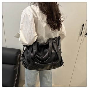 Large black leather tote bag with dual straps shown on model for size perspective