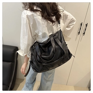 Close-up of black tote bag featuring soft leather texture and adjustable shoulder strap