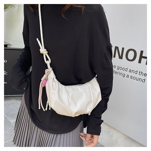 Detail of cream crescent bag with pleated PU leather, pink heart charm and knot strap