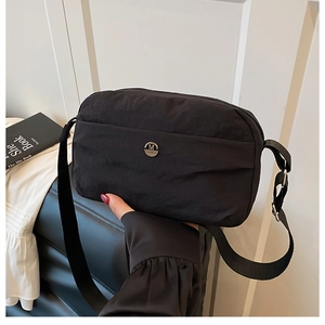 Lightweight black waterproof nylon crossbody bag featuring stylish pleated design and metal logo