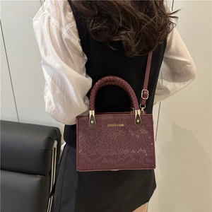 Burgundy snakeskin embossed square handbag with woven handle and gold hardware detail