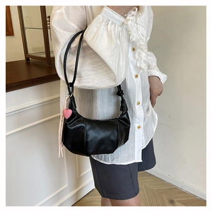 Détail du sac croissant noir avec breloque cœur rose et inscription fashion