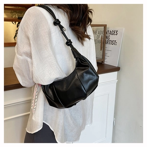 Detail of black pleated crescent bag featuring a unique knotted long shoulder strap