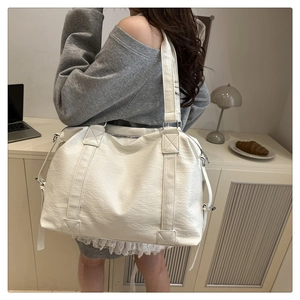 Close-up of white oversized faux leather tote bag with pebble grain texture and metal buckle