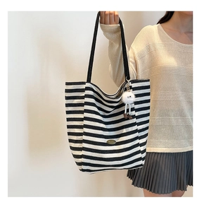 Nahaufnahme der schwarz-weiß gestreiften Canvas-Tasche mit süßem Plüsch-Anhänger