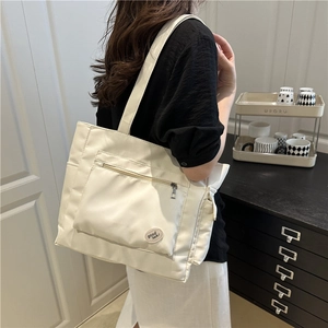 Minimalist white canvas tote bag with front zipper pocket and good luck slogan patch