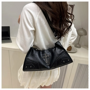 Detail of black pebbled leather texture with silver cross and stud accents on shoulder bag