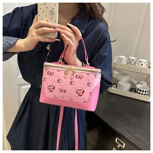 Close-up of pink cherry print handbag with double zippers and top handle details