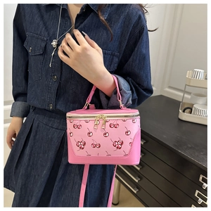 Detail of pink box crossbody bag with cherry prints and gold hardware accents