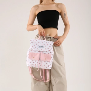 Floral print backpack for women with drawstring flap and pink pocket accents in studio