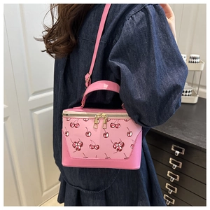 Detailed close-up of pink bucket bag featuring red cherry prints and golden zippers