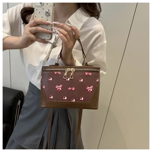Detail of vintage bucket bag with red cherry print and golden zipper closure on PU leather