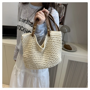 Dettaglio ravvicinato della borsa a tracolla in cotone beige con manici in pelle marrone