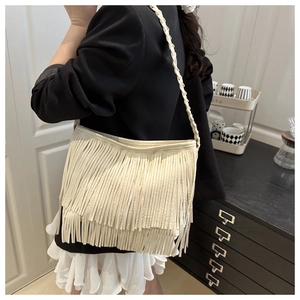 Détail d'un sac cabas en cuir blanc cassé avec de longues franges doubles et bandoulière