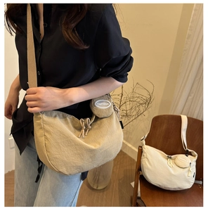 Detail of a nylon crescent crossbody bag with a round mini pouch and wide canvas strap