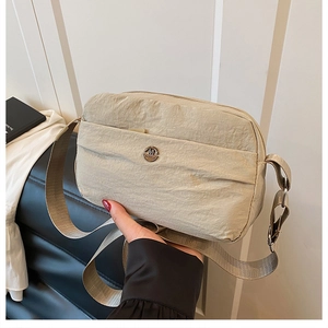 Light beige waterproof nylon crossbody bag with adjustable wide strap and metal logo